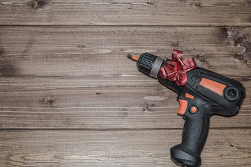 A screwdriver with a red bow as a gift to a man for a holiday. Father's Day, February 23, men's holiday, New Year and Christmas.