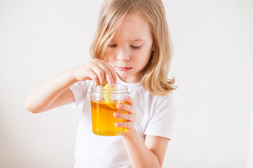 A little girl holds a jar of honey and a slice of apple in her hands. Symbols and traditions of the Jewish New Year. Rosh ha Shana