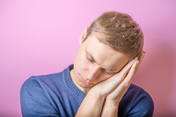 Fototapeta premium Young Man wants to sleep. Put his head in his hands. Gesture. On a purple background.