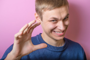 Young man scared smiling, joking. Gesture. On a purple background.