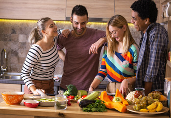 Group of friends preparing vegetarian meal.They preparing food and making fun in the kitchen.	
