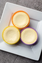 Mini cheesecakes with whipped cream topping, healthy summer treat on grey stone table
