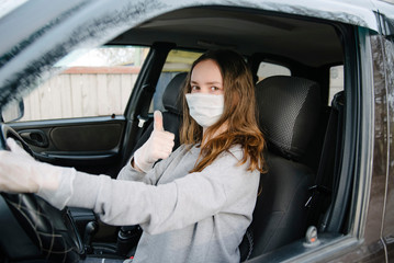 Naklejka premium a Female driving car wearing protective face mask and gloves