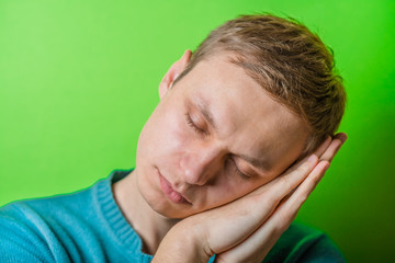 young man dozing on green background