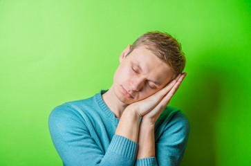 young man dozing on green background