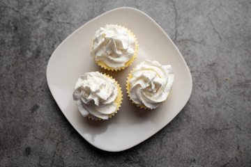 Three mini cheesecakes on a white plate with whipped cream icing 