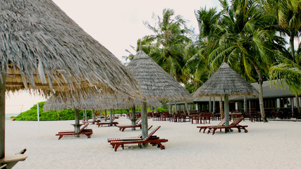 Tropical beach with wooden deck chairs and umbrellas. Deserted beach without tourists