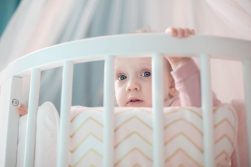 one year old baby girl peek out of bed