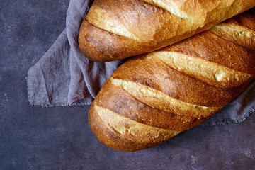 Fresh loaf on a brown background.  Traditional wheat freshly rustic baked bread, loaf of bread.