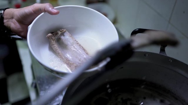 Close up scene of serving Bak Kut Teh with the pork ribs into the bowl, food processing, Malaysian and Singaporean traditional dish, cooking step, food preparation, the famous dish.