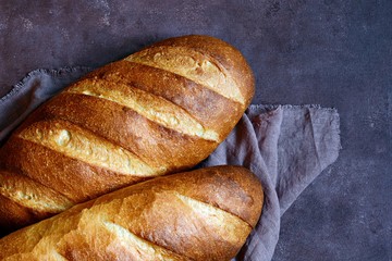 Fresh loaf on a brown background.  Traditional wheat freshly rustic baked bread, loaf of bread.