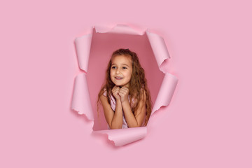 Portrait of beautiful happy smiling caucasian little girl posing in pink paper hole. the child is waiting for a gift. banner for discounts and sales