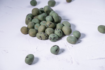 Green wasabi snack on white textured background. Close up view.