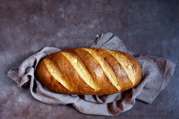 Fresh loaf on a brown background.  Traditional wheat freshly rustic baked bread, loaf of bread.