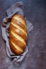 Fresh loaf on a brown background.  Traditional wheat freshly rustic baked bread, loaf of bread.