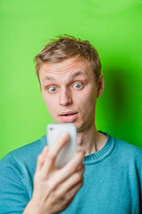 A confused young man looking at mobile phone