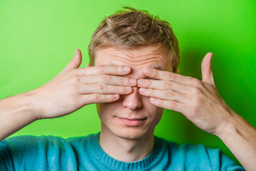young man closes his eyes with his hands