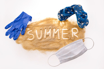 Brown sand on a white background. The inscription SUMMER on the hub, a protective mask around the sand and blue gloves. A vision of summer in 2020 during the Coronavirus pandemic. Summer in Covi-19