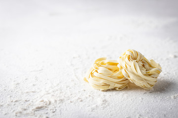Raw uncooked homemade italian pasta tagliatelle on a light background
