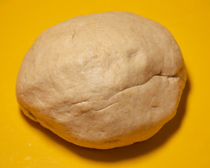 Fresh raw dough ball isolated on a yellow background