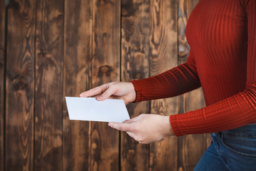 The person holds a white envelope. Sending a letter. brown background