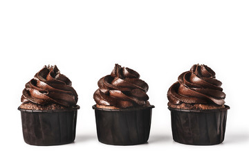 Three delicious chocolate cupcakes with gold sparkles sprinkled on chocolate icing on isolated white background. Mockup for your design. Close-up. Place for text.