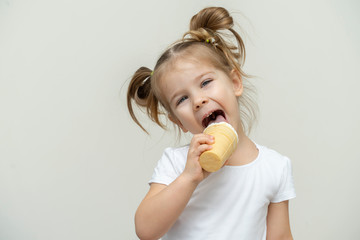 3-4 years old girl in a white t-shirt eating ice cream and smiling. happy face and laugh