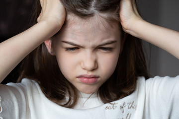 Naklejka premium the girl is crying, grabbed her head, a child’s problems. The girl scratches her head, severe itching, infection with lice