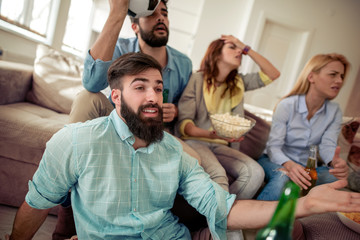 Young friends drinking beer and watching tv at home