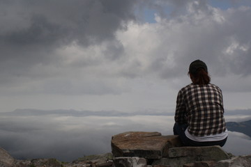 near 1500m above sea level, girl is sitting among clouds. on top of the world