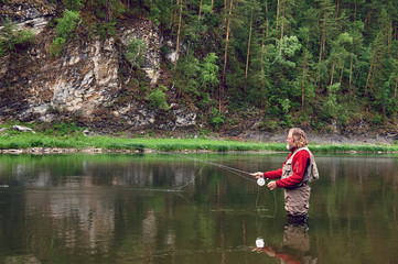 fly fishing angler makes cast while standing in water