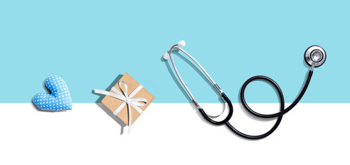 Stethoscope with a gift and a heart cushion - flat lay