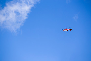 Red rescue helicopter moving in blue sky