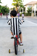 An Asian boy child ride bike in the street at the home village. boy rides a bicycle to play at the playground.