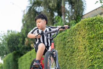 Fototapeta na wymiar An Asian boy child ride bike in the street at the home village. boy rides a bicycle to play at the playground.