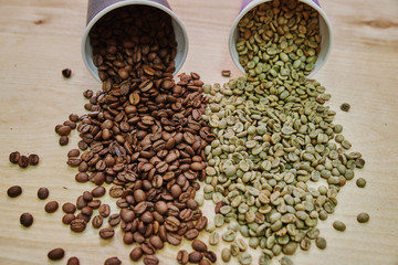 Coffee beans before and after roasting. Brown and green grains scattered on the table