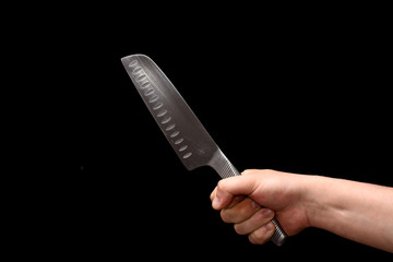 big sharp knife in a hand on a black background.