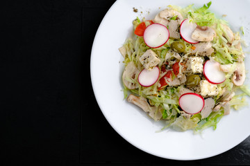 Salad of young cabbage, tomatoes, radishes, greens with olives, chicken and feta cheese. Top view copy space.