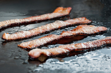 bacon strips being fried on a snack plate
