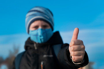 a masked boy protects himself from the virus and holds a thumbs up