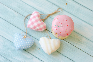 Sweet bread traditional easter orthodox celebration cake panettone also called kulich glazed with pink icing and raisins and three colored hearts on blue wooden background