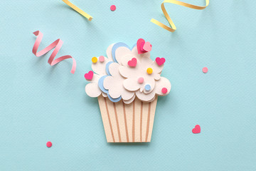 Paper cutting cupcake on blue background. Handmade art work. Colorful sprinkles, dot and star, for...