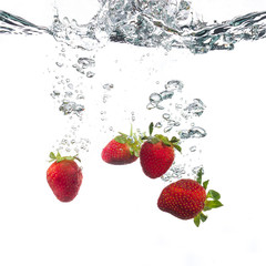 Red strawberries splashing on water in a white background