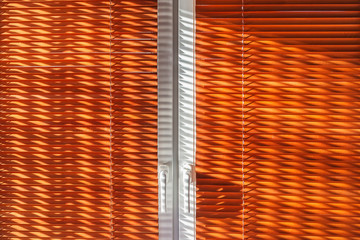 The geometrical beautiful sun's rays on the closed wooden blinds to the window curtain. Texture background