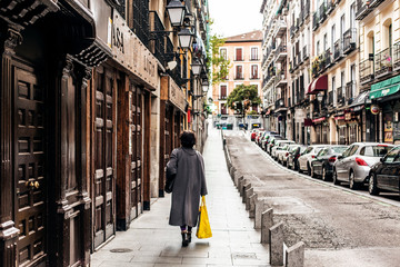 Señora con abrigo largo va a comprar en el centro de Madrid vacio debido al confinamiento derivado de la pandemia mundial covid-2019