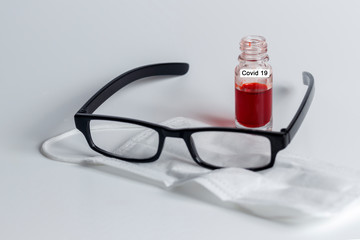 Covid-19 Blutproben Flasche mit Mundschutz und Lesebrille