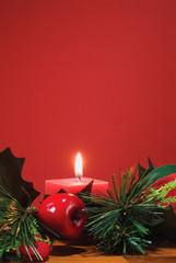 A red candle with christmas like ornaments on a wooden tabletop with a lot of copy space in the upper part of the image.