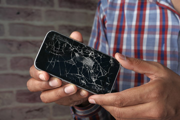Close up of man hand holding broken smart phone 