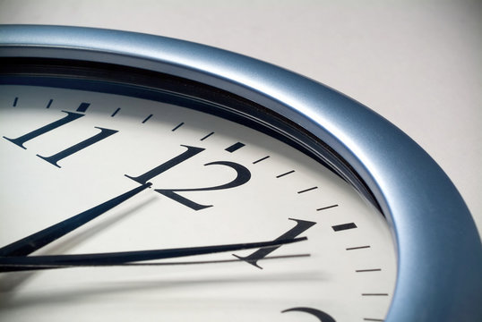 A close up of an analog clock displaying 12 o clock.