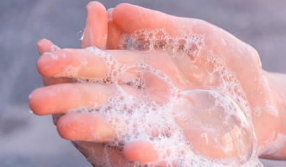 Soap foam on  child hands. Covid - 19 Coronavirus prevention. A child wash our hands with antibacterial soap. Coronavirus  pandemic protection by frequent hand washing. Selective focus